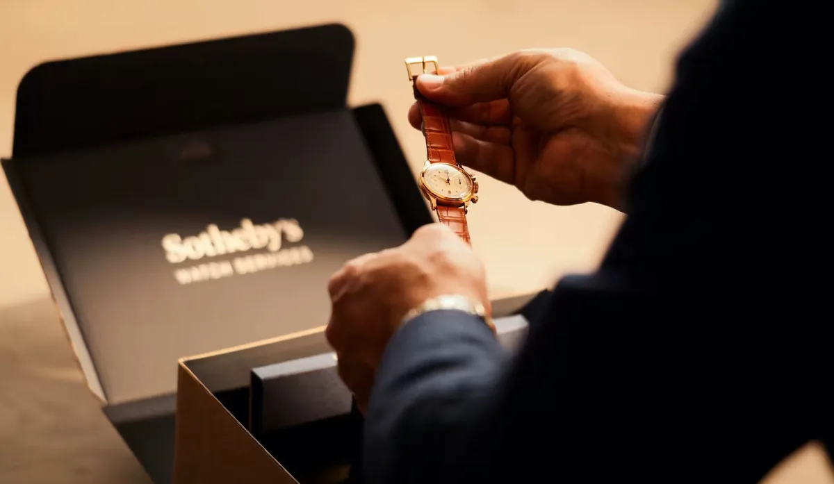 Person holding a Rolex watch with a box and papers.